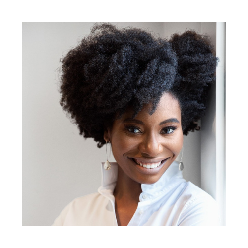 Whitney A. White with a radiant smile and voluminous natural hair.