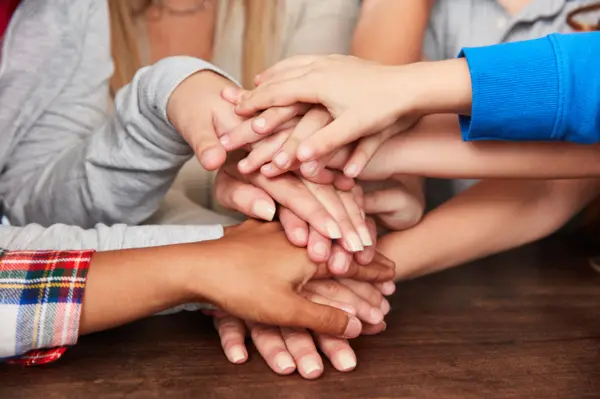 children's hands stack on top of one another embodying the importance of creating inclusive school environments